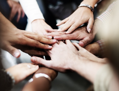 A group of people put their hands together in a circle.