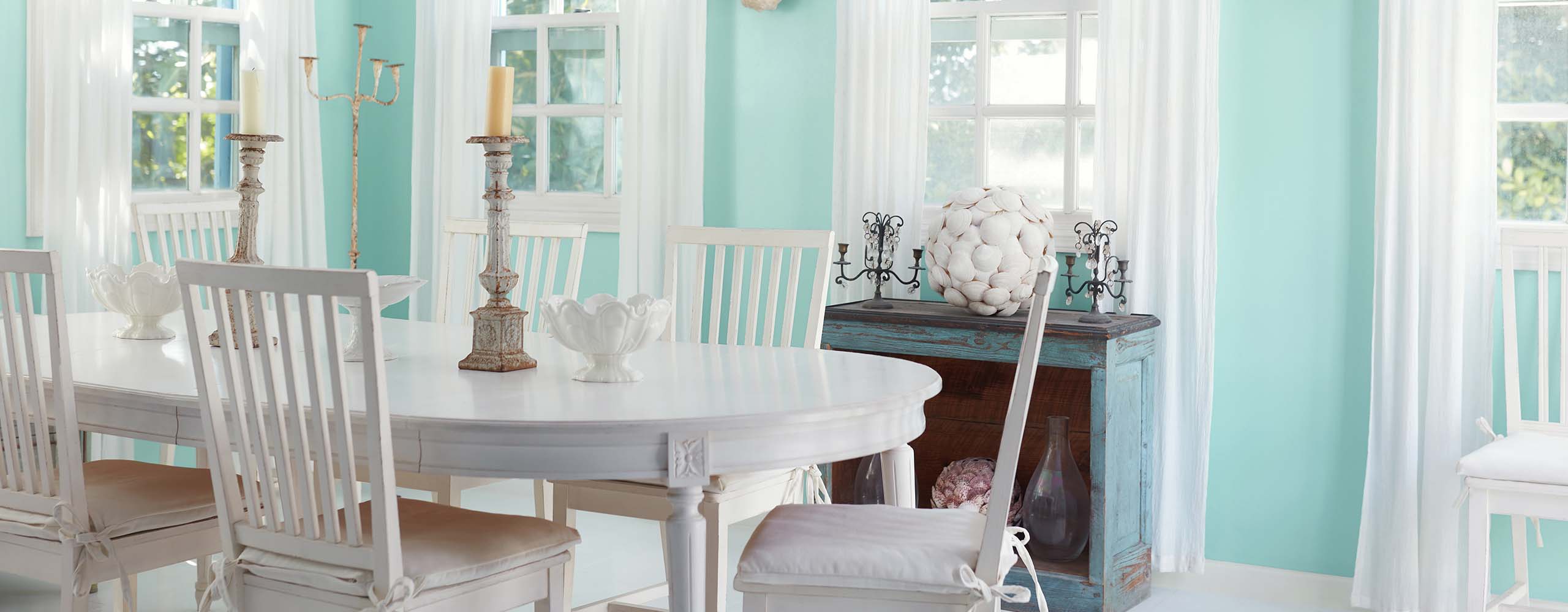A pretty, light turquoise painted dining room with white trim, a white shiplap ceiling, and white dining furniture. A pretty, light turquoise painted dining room with white trim, a white shiplap ceiling, and white dining furniture.