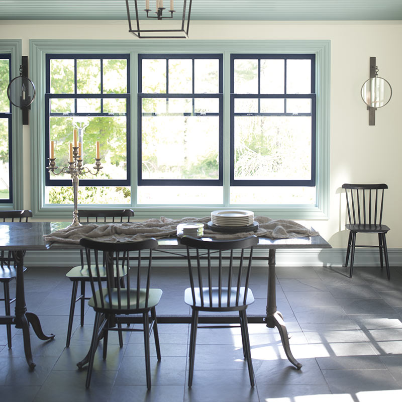 Three windows trimmed in both navy and light blue create a light-filled panorama in an off-white dining room. Color of the Year 2019