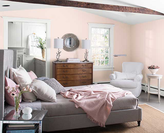 A bedroom with walls painted in Mellow Pink 2094-70, displaying the impact of warm paint colors