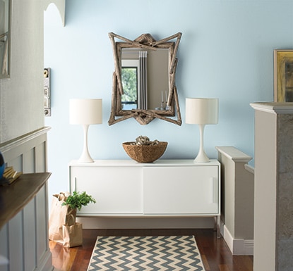 Décor aux murs bleu pâle encadrés d’une table d’accoudoir sur laquelle reposent deux lampes blanches assorties
