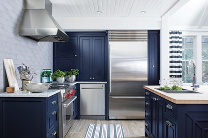 Sunny, modern kitchen with blue cabinetry and stainless steel appliances.
