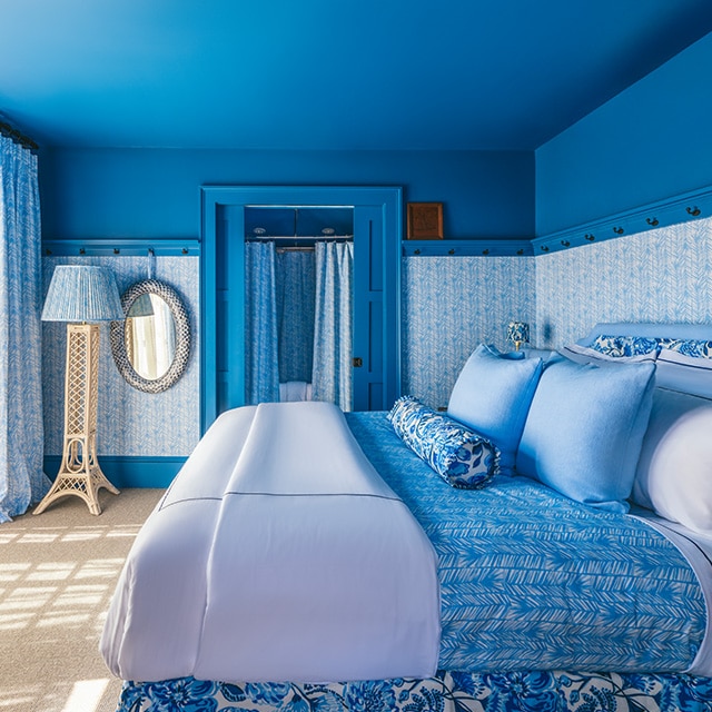 A pretty, blue painted bedroom with blue patterned wallpaper, and blue and white bedding and decor. A pretty, blue painted bedroom with blue patterned wallpaper, and blue and white bedding and decor.