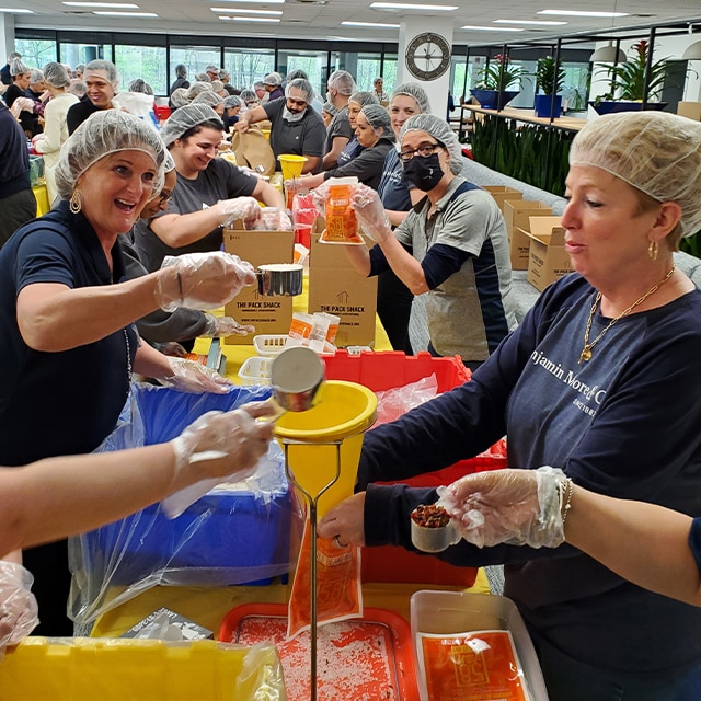 Benjamin Moore Montvale employees participate in a volunteer party, packing food kits for a Community Food Bank.
