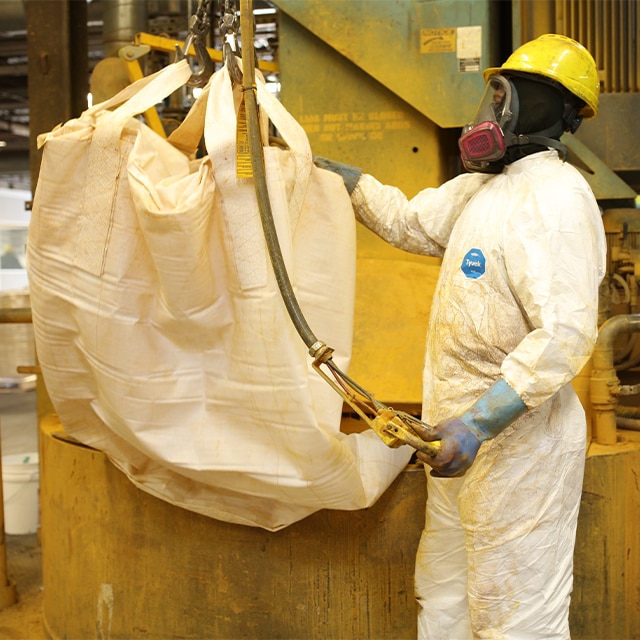 A Benjamin Moore employee wearing safety equipment and white coveralls works in the Newark facility processing paint.