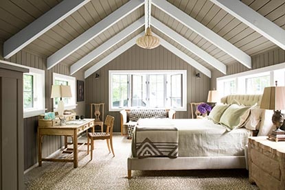 Une chambre à coucher richement meublée avec un plafond incliné gris et blanc.