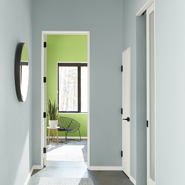 Un pasillo alegre pintado de azul con marco blanco, puertas y techo abovedado con revestimiento, y una habitación pintada de verde brillante en el fondo.