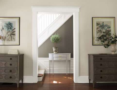 A gray and neutral hallway leads to a white staircase.