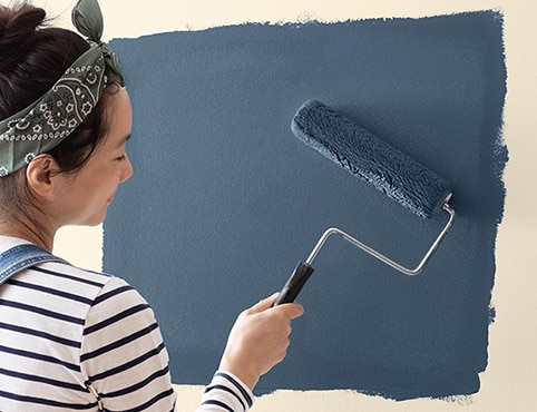 Dueña de casa pintando una pared con un rodillo de buena calidad.
