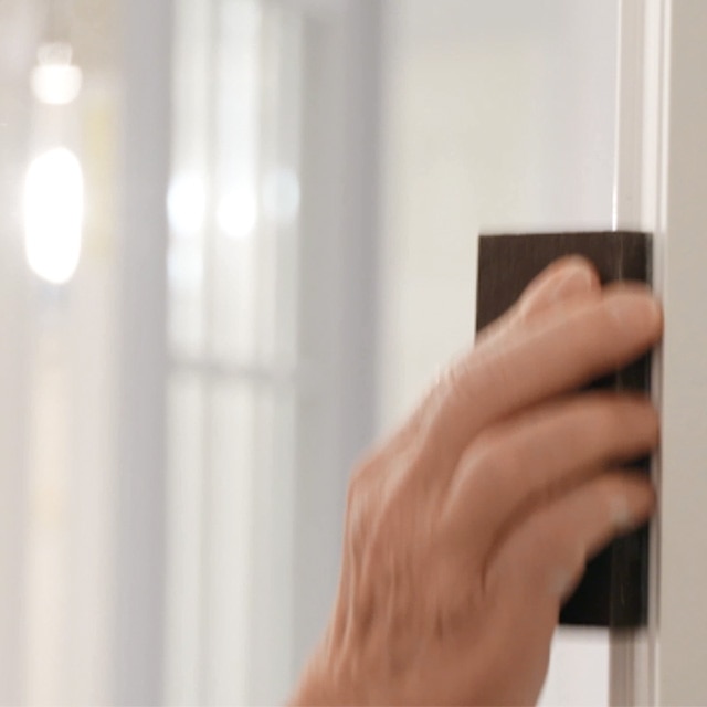 A person sanding white painted trim.