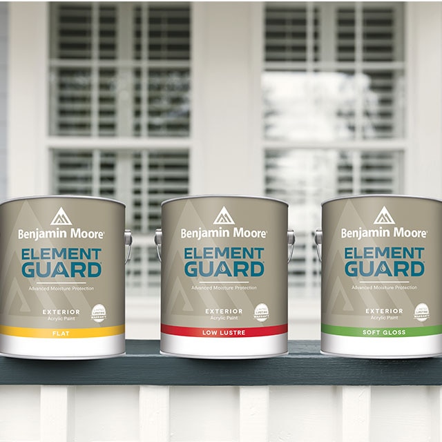 Three cans of Element Guard™ exterior paint sitting on a blue and white porch railing, in front of a window.