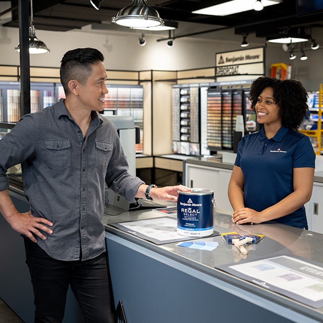 A Benjamin Moore store professional sells paint and supplies to a customer.