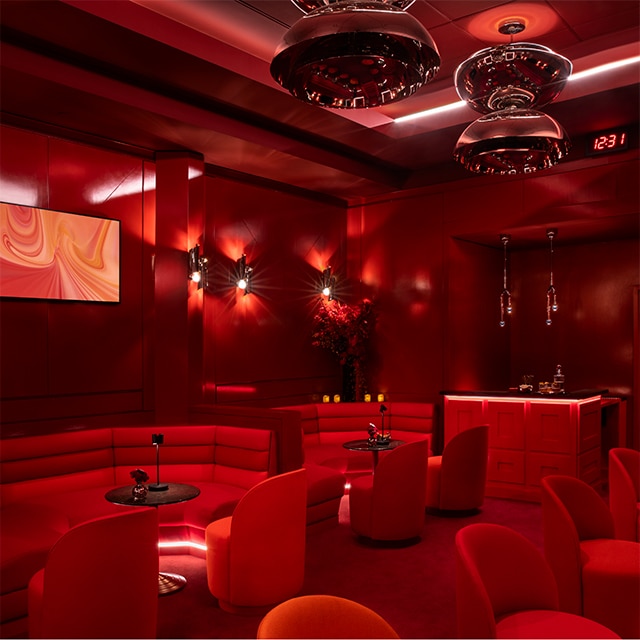 Booths and seating under red lighting at the Benjamin Moore lounge at Madison Square Garden. 