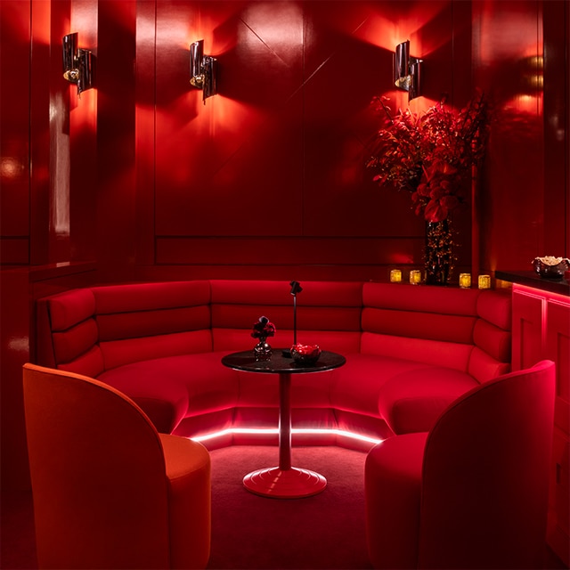 Large circular booth with overhead red lighting and red-painted walls in Benjamin Moore lounge. 